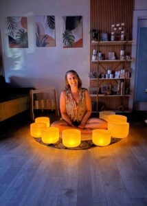 Laura Mae seated with glowing crystal singing bowls